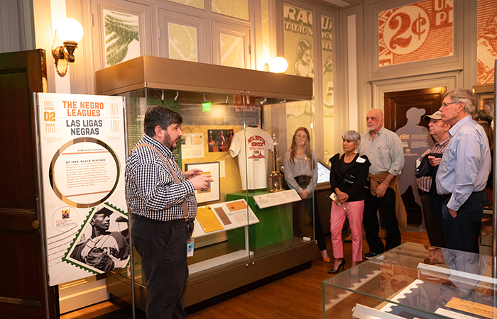 Daniel Piazza G’04 takes the group on a tour of the exhibit